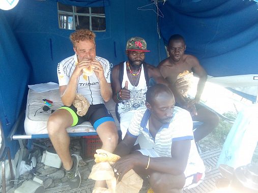 Dal racconto di Tommaso: "Eric, ghanese di Kumasi, il ragazzo col cappellino, mi porta dai suoi compagni di tenda Ibrahim (Gambia) e Lountan (Senegal). Ci presentiamo, riesco a strappare dalle loro facce malinconiche qualche timido sorriso. Io tiro fuori i miei panini con la frittata, che condividiamo con altri loro compagni di campo (in queste tende abitano circa 500 ragazzi africani), mentre loro tirano fuori dal frigo bottiglioni di acqua fresca e succo di frutta. Il mio ultimo pranzo-ospitata del viaggio in bici può avere inizio. Fa molto caldo e le mosche non ci danno tregua. I ragazzi sono incuriositi dal mio giro d'Italia e dalla mia bici. Ognuno di loro ne ha una. Il villaggio è costellato di biciclette ammassate in ogni dove. "Le usiamo per andare sui piazzali dove i camioncini si fermano a caricarci per portarci a lavorare nelle terre", mi racconta Eric. "Ma la stagione forte è solo quella delle arance. D estate coi pomodori e altri ortaggi si lavora solo un giorno ogni 3 o ogni 4, 40 euro al giorno se va bene". E quando non si lavora la vita nella tendopoli scorre lenta: "per fortuna ci sono acqua ed elettricità, e non paghiamo l'affitto, ma senza soldi e lontano da tutti è molto triste". In effetti il paese di Rosarno è lontano più di 5 chilometri, ma sopratutto sono lontane le famiglie lasciate in Africa, dietro il sogno di un ricongiungimento diventato col passare degli anni sempre più un illusione. Ci sono ragazzi che passano di qui solo per poche settimane, ma altri che si sono adagiati e vivono qui da anni. "Mia moglie mi ha lasciato", mi racconta Eric: "Sono 7 anni che non ti fai vedere, non posso rimanere da sola, mi ha detto. Però con nostro figlio sono ancora in contatto. Faccio la videochiamata tutti i giorni". Ci scambiamo il numero di telefono con la speranza di rimanere in contatto"